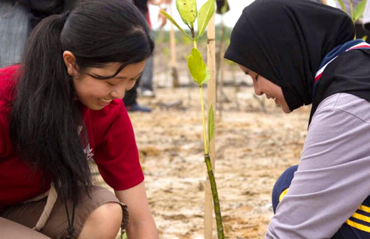 Two girls preserving nature by planting tree shoots.