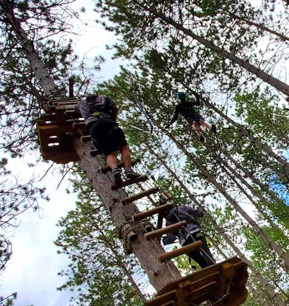 1st Lakeshore Ridge Venturer Company are shown climbing obstacles and challenges among the trees.