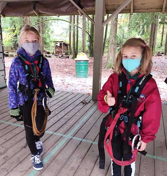 Two 1st Haney Scouts in safety harnesses and face masks preparing to hit the tree tops.