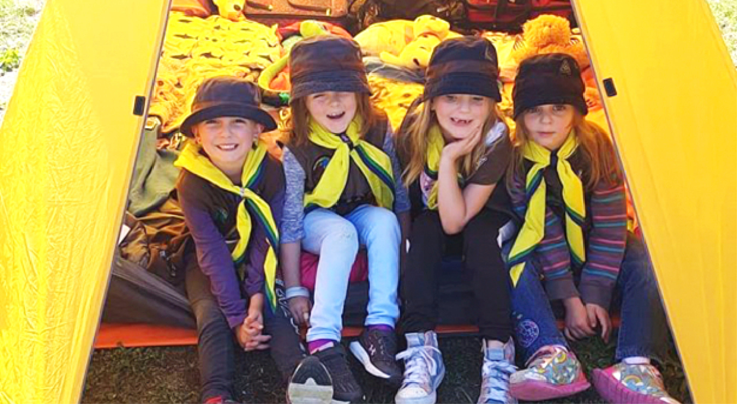 Four girl Beaver Scouts sitting together and posing for the camera while smiling and having fun.