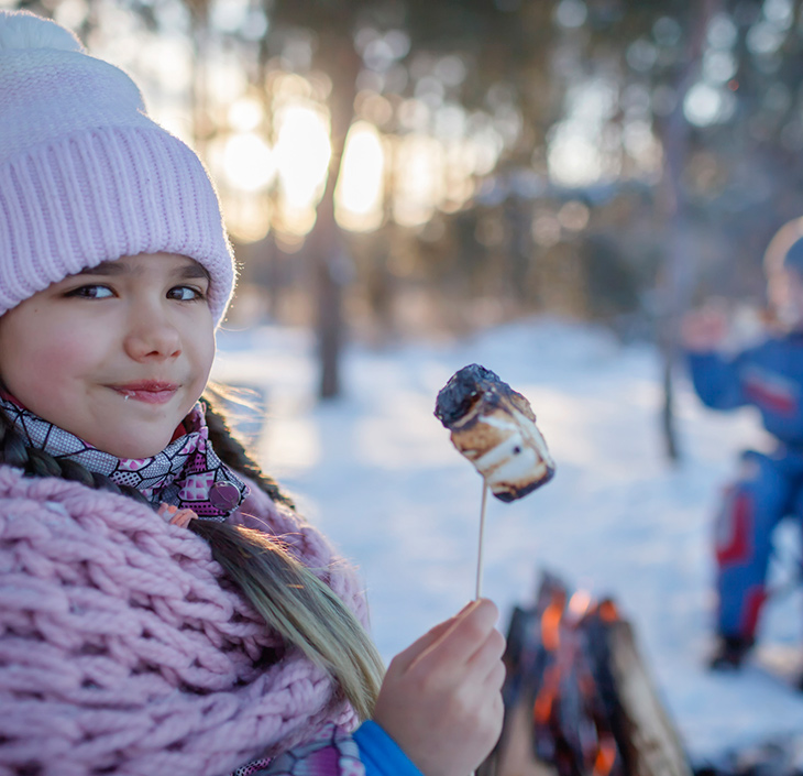 Girl roasting marshmallow in winter