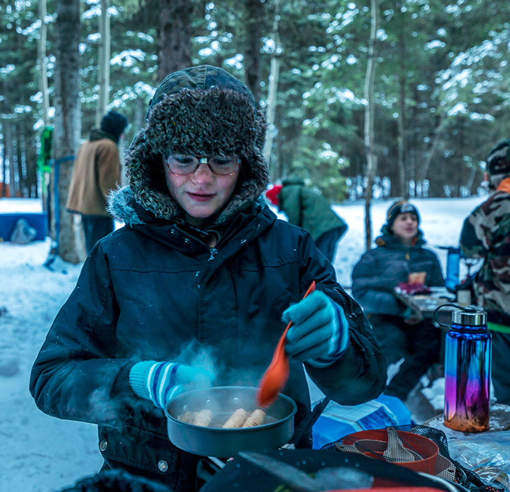 Youth cooking a meal at winter camp
