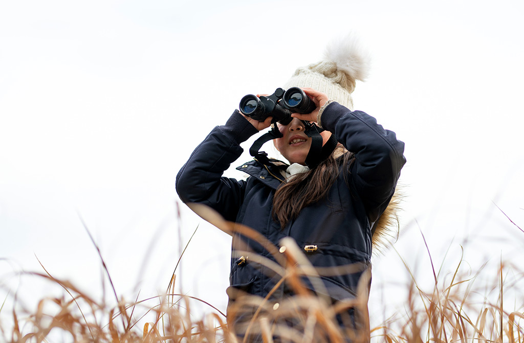 Girl looking with binoculars in winter